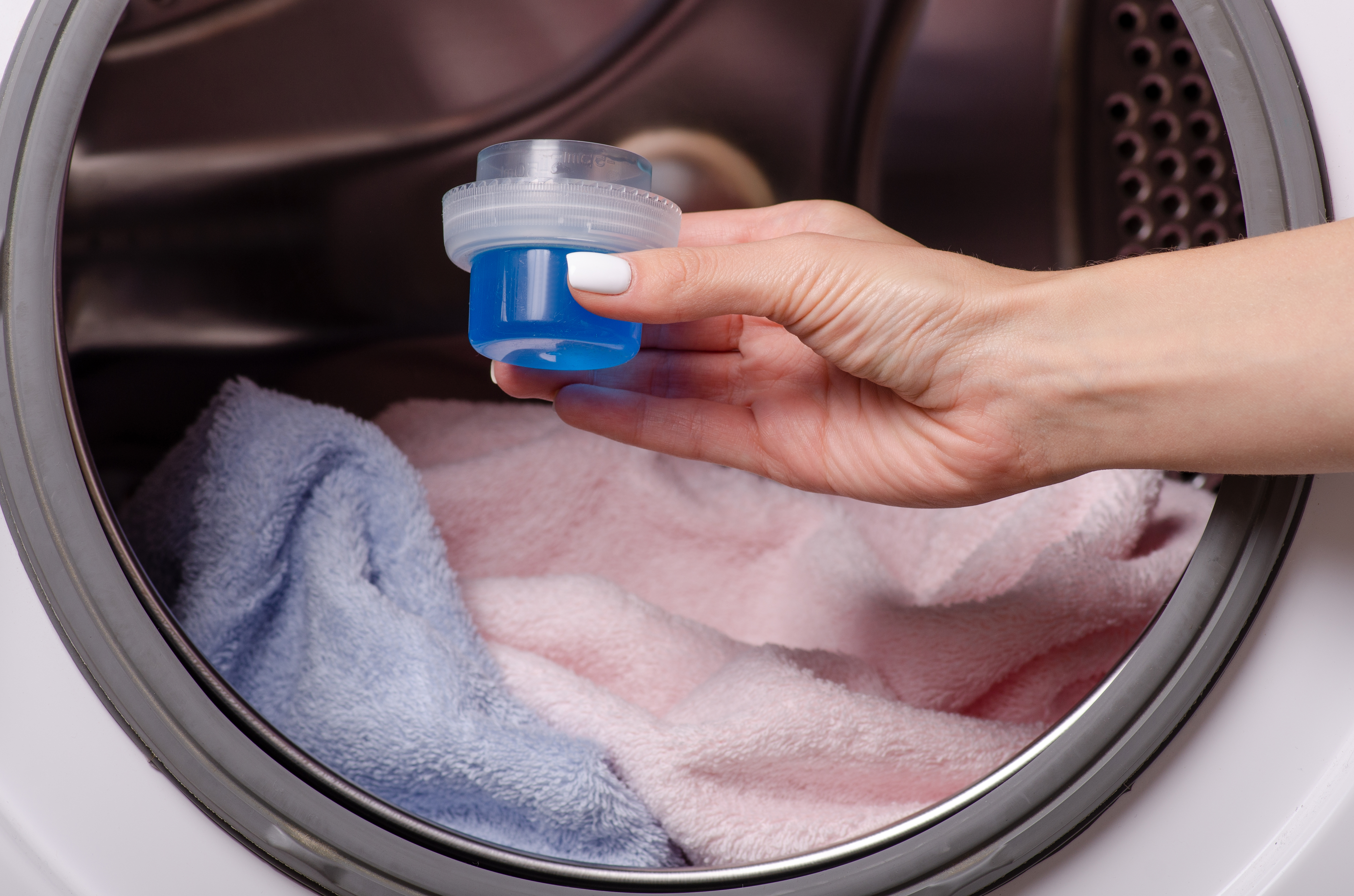 Hand pouring laundry detergent into washing machine